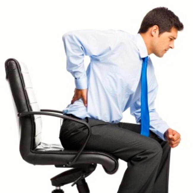 Trabajador sentado con dolor de espalda.   